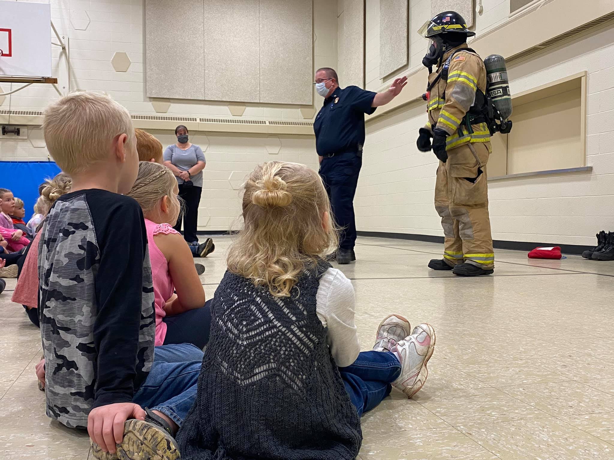 Firefighter geared up showing students