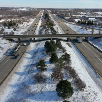 drone view of bridge over double highway with snow on the ground