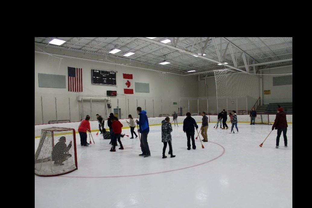 Teens on the ice playing broom ball